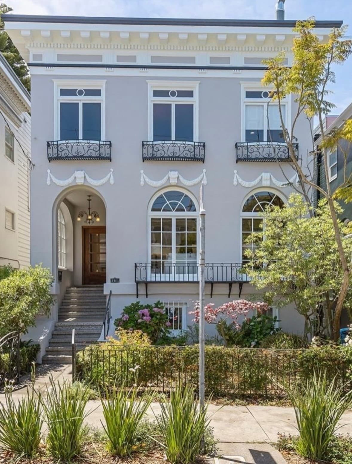 A classic San Francisco Italianate home with arched windows, an ornate white cornice, and wrought-iron balconies
